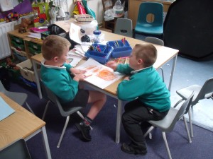 At school, two boys 5-6 yrs share their journal pictures